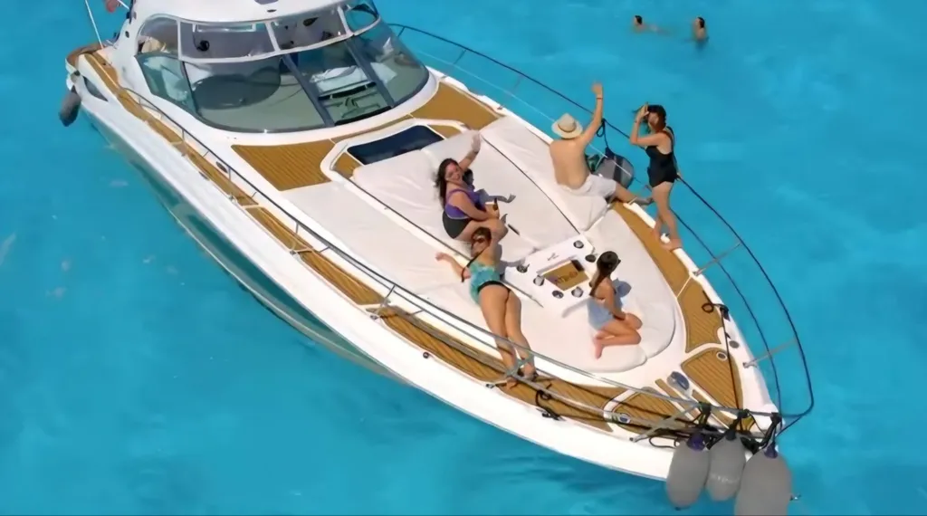 Guests on the bow of a private yacht in turquoise water off Isla Mujeres